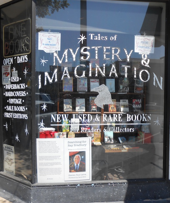 The storefront window of Mystery & Imagination bookstore at 238 N. Brand Blvd, Glendale, with 'Searching for Ray Bradbury' by Steven Paul Leiva displayed in the window